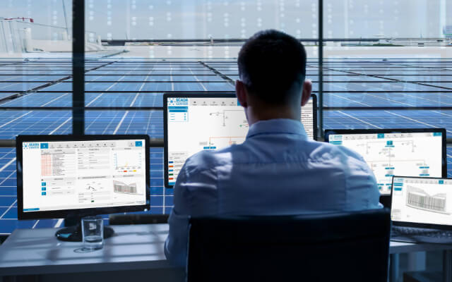 man working on several monitors with a view of a PV roof system