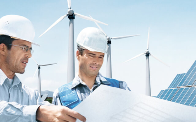 two men analysing a big sheet of paper, in the background wind trubines and a pv plant