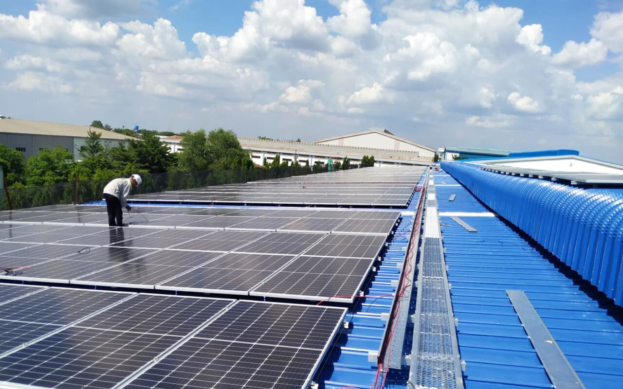man on the roof of the Dong Nam Viet Packaging company building to install and commission the PV system